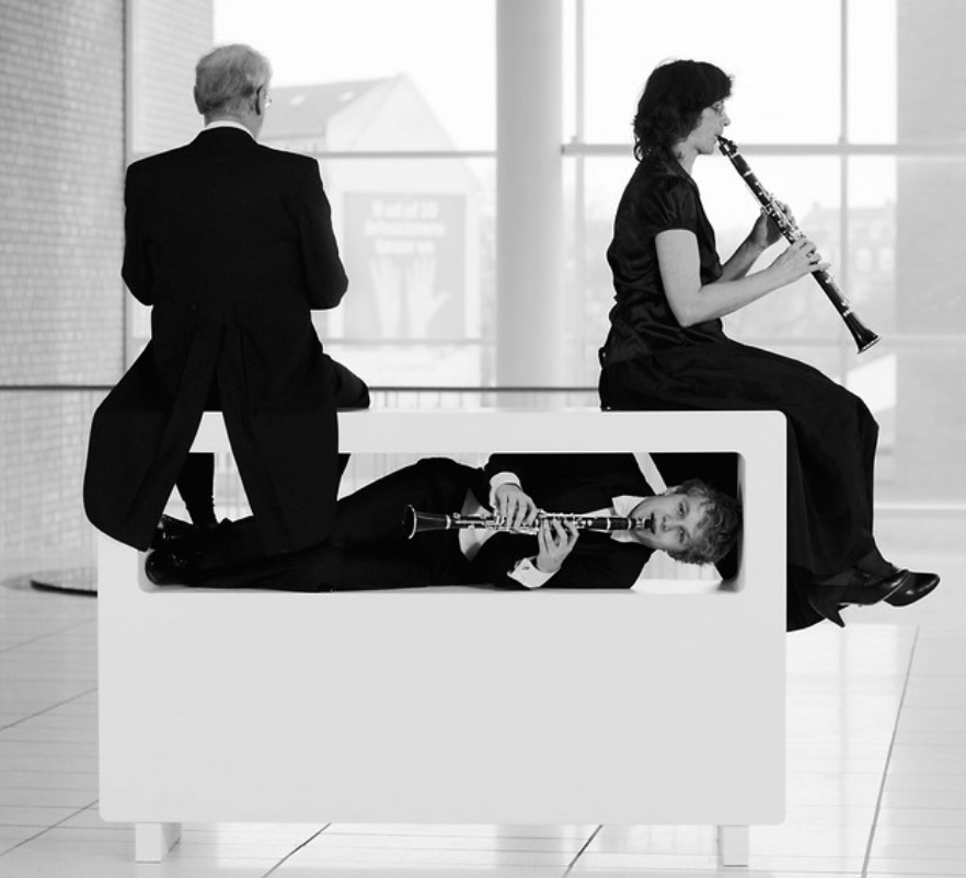 Trio de clarinettistes autour d’un banc blanc